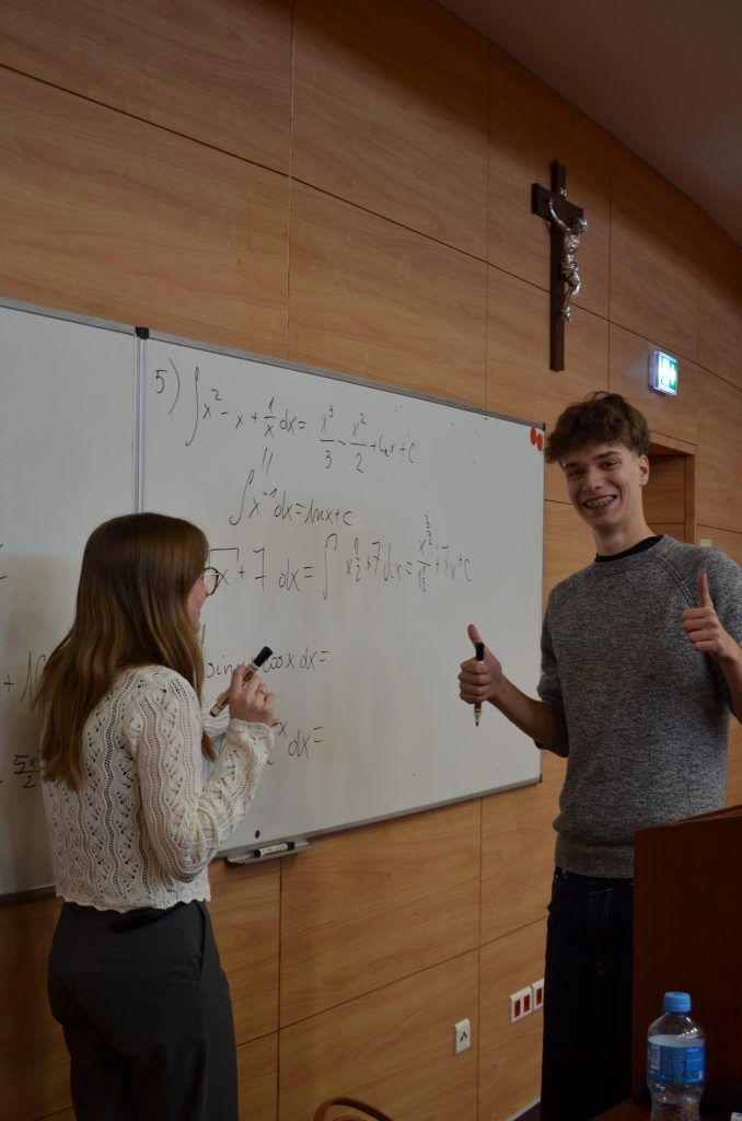 zadowolony uczeń LO przy tablicy rozwiązujący zadania z matematyki
